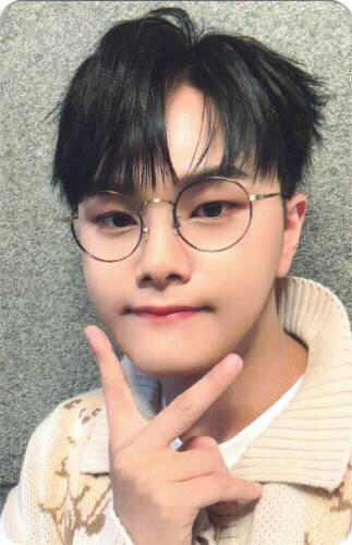 Photocard of Jahan making a peace sign under his chin and wearing a bear sweater and glasses