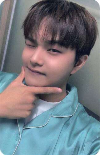 Photocard of Jahan in blue pajamas making a checkmark hand under his chin