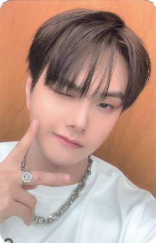 Photocard of Jahan in a white shirt and chain necklace, making a peace sign and winking