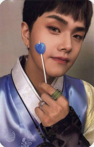 A photocard of Jahan wearing a blue hanbok and holding a blue lollipop to his face