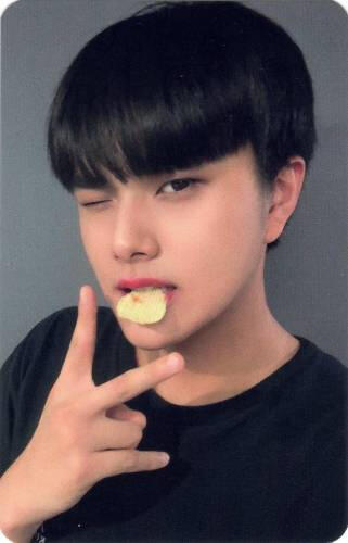A photocard of Jahan holding a chip between his teeth, winking, and holding up a peace sign