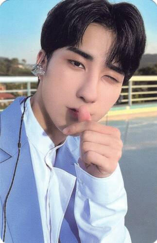 Photocard of Harin wearing a light blue suit and making a finger heart in front of his mouth