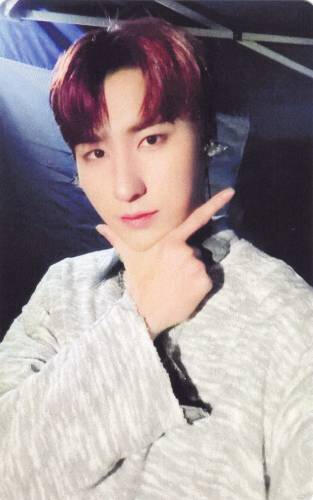 Photocard of Harin holding his hand in a check shape under his face