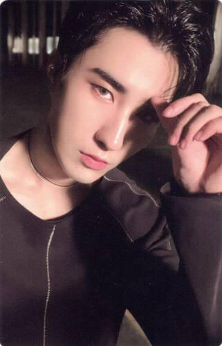 Photocard of Harin wearing a black long sleeve shirt and holding a hand in front of his eye