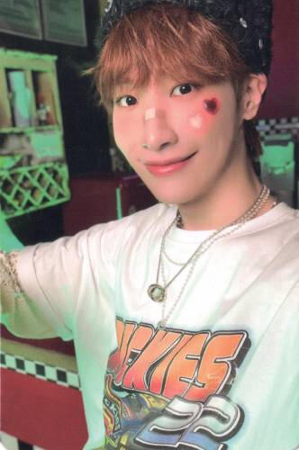 Photocard of Dongmyeong wearing a white graphic shirt with hearts on his cheek