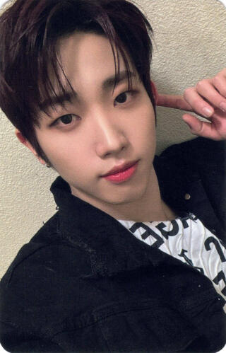 A photocard of Dann wearing a black denim jacket and white shirt