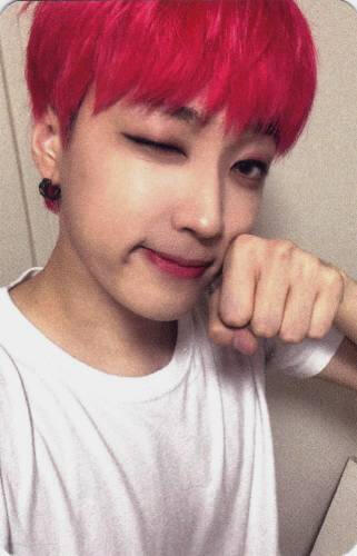 A photocard of Arthur with bright red hair winking and making a pawed fist