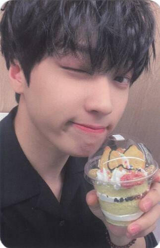 Photocard of Arthur winking and holding a pastry by his face