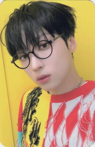 Photocard of Arthur wearing a patchwork sweater and black glasses