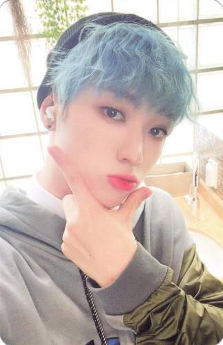 Photocard of Arthur wearing a hoodie with blue hair and making a checkmark symbol under his chin
