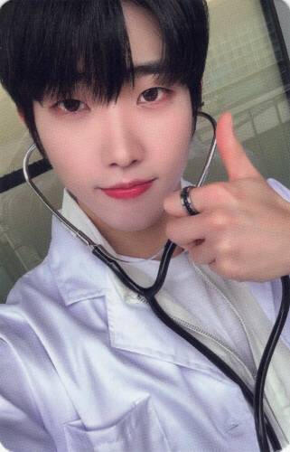Photocard of Dann wearing a doctor's coat and stethoscope, making a thumbs up
