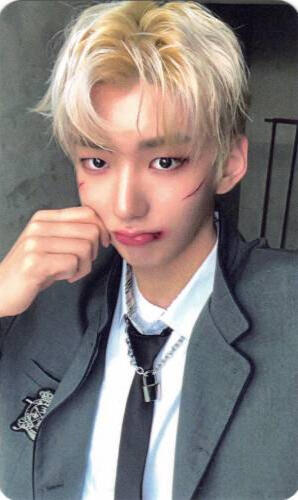 Photocard of Hwon wearing a grey school uniform with cuts on his face and pinching his cheek