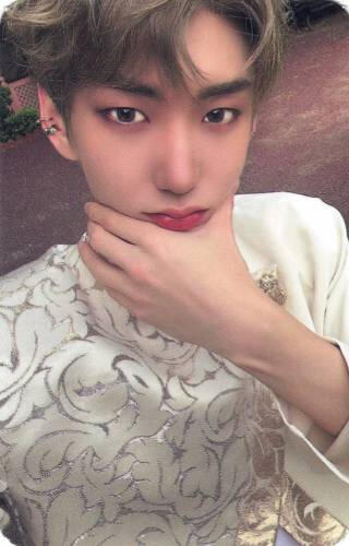Photocard of Hwon wearing a white and gold outfit and cupping his face