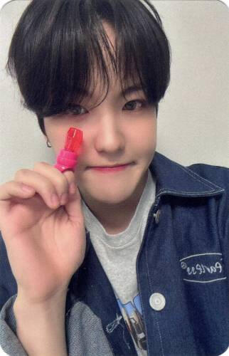 Photocard of Louis holding a ring pop to his face and smiling