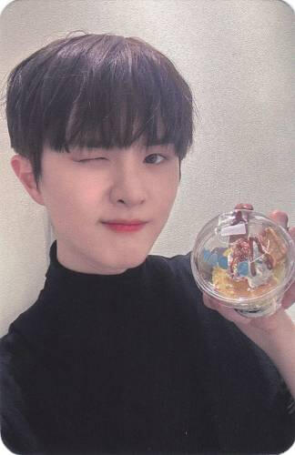 Photocard of Ivan holding a pastry out and winking