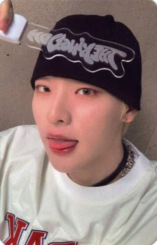 Photocard of Mujin wearing a white shirt and black beanie, sticking his tongue out, and holding the Realize lightstick