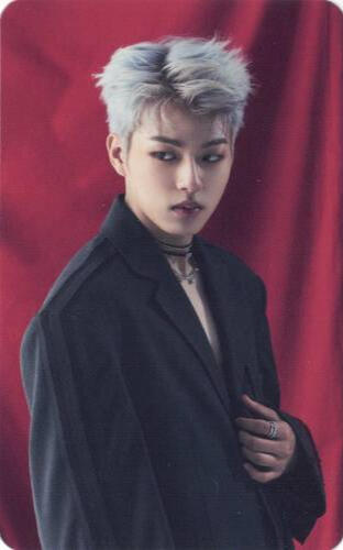 Photocard of Jinwoo from Ghost9 holding the edge of his black suit jacket and gazing off to the side in front of a red curtain