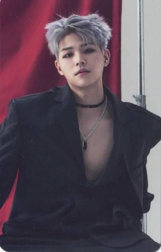 Photocard of Junhyung from Ghost 9 wearing an open black suit jacket and choker, sitting in front of a red curtain