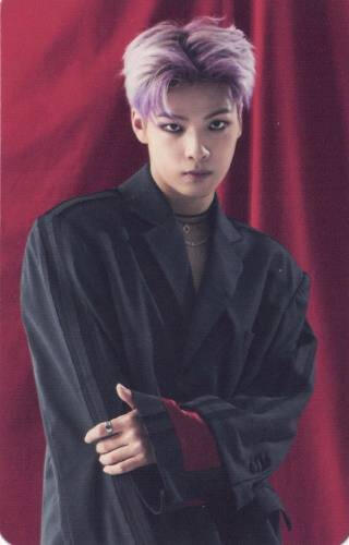 Photocard of Junseong from Ghost9 wearing a black suit jacket and choker and holding one arm, stood in front of a red curtain