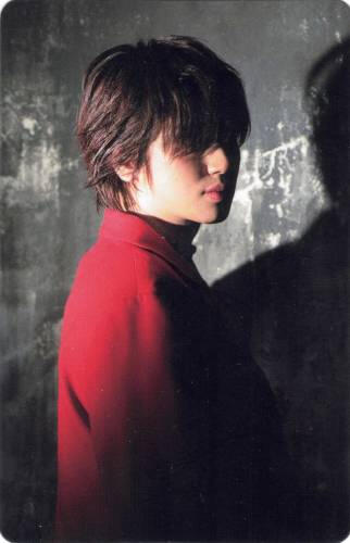 Photocard of Niel in a red jacket turning back to face the camera, his face in shadow