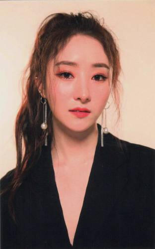 Photocard of Sua wearing a deep black v-neck and staring at the camera