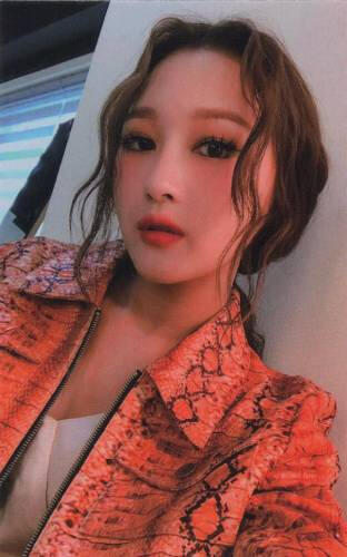 Photocard of Siyeon wearing a watercolour orange jacket and staring down at the camera