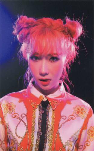 Photocard of Handong with bright orange hair in space buns staring at the camera, tongue slightly out