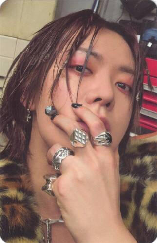 Photocard of Yuta wearing chunky silver rings and gripping his face