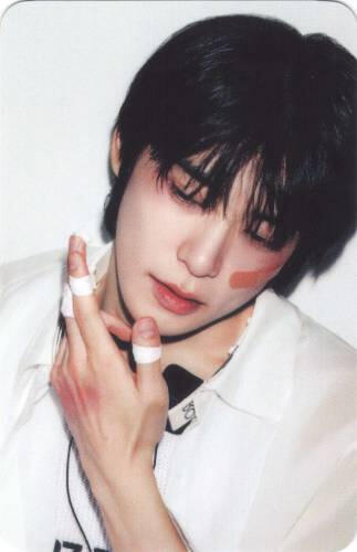 Photocard of Jaehyun looking down to the side with bruises on his hand and face