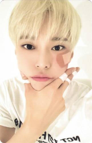 Photocard of Doyoung cupping his face with a large bandaid on his face