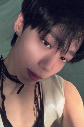 Photocard of Hwanwoong wearing a silver vest and low-cut black shirt looking up at the camera