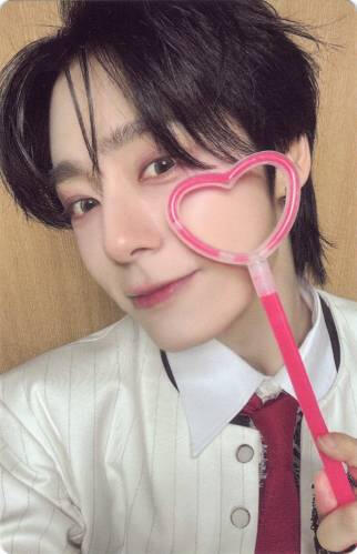 Photocard of Hwanwoong holding a glowstick heart wand to his face