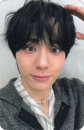Photocard of Hwanwoong making a puppy ear with his hand and smiling