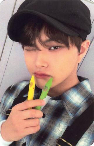 Photocard of Jahan holding two crayons to his mouth and winking