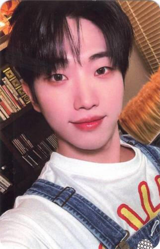 Photocard of Dann smiling and holding a paintbrush by his face