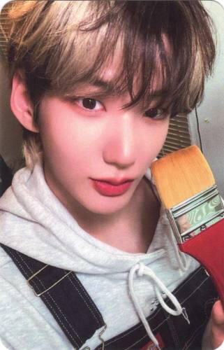 Photocard of Hwon holding a paint brush to his face