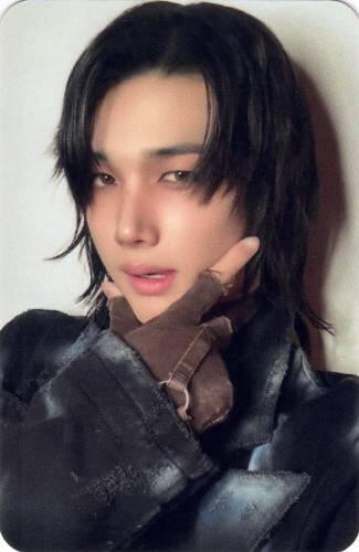 Jo in a black outfit with long black hair and making a checkmark under his chin
