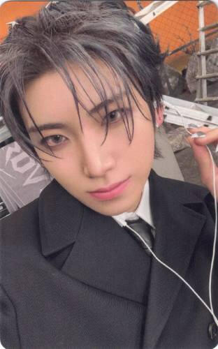 Photocard of Yuma with earbuds in, holding one earbud out