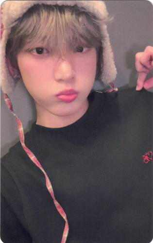 Photocard of Harua wearing a red plaid hat and puffing his cheeks out